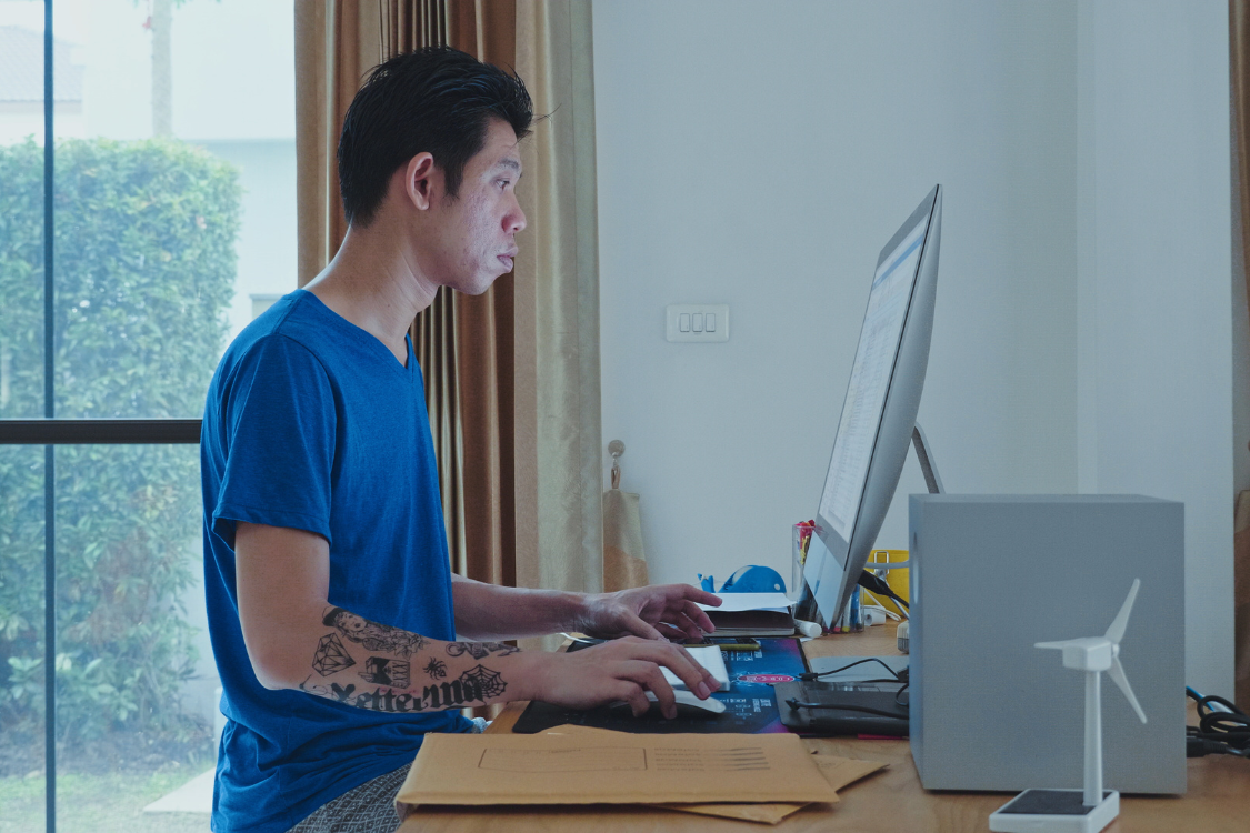 Filipino remote worker using a desktop computer at a tidy home office.