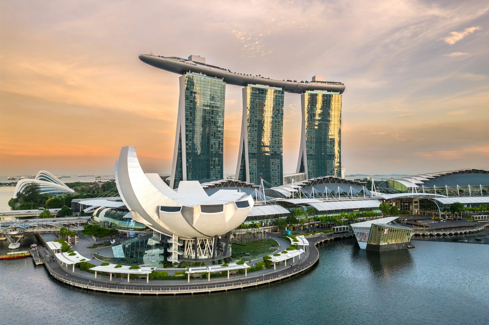 Futuristic view of Marina Bay Sands, Singapore, at sunset. The iconic structure features three towers topped by a boat-shaped sky park, reflecting in the bay.