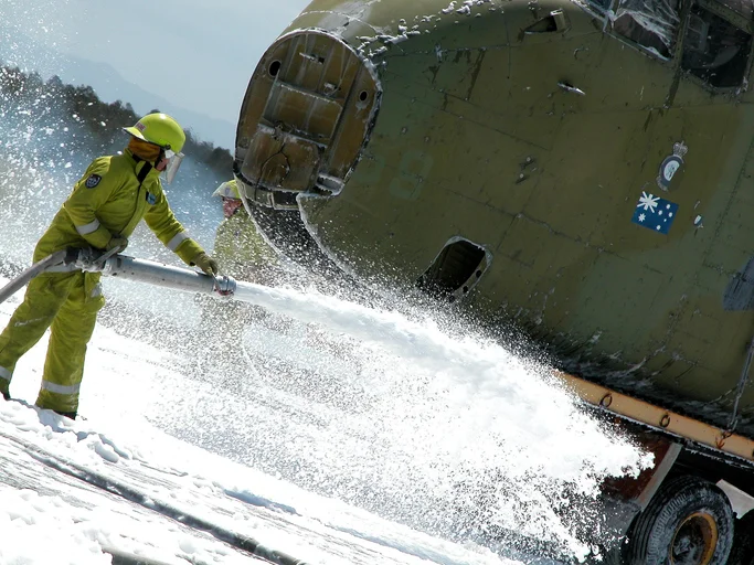 A firefighter suppressing fire with firefighting foam.