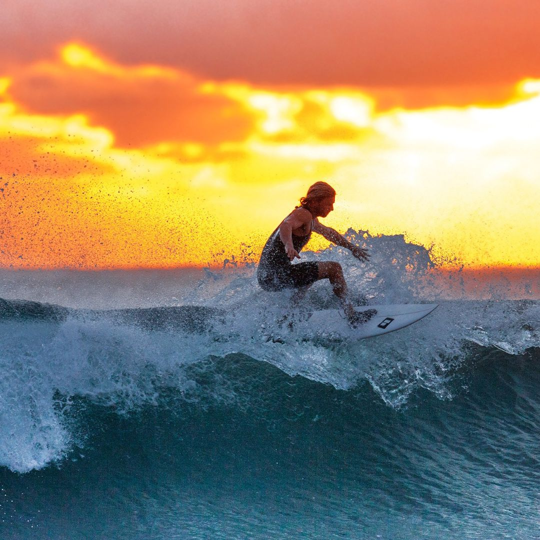 man surfing a wave in the ocean at sunset