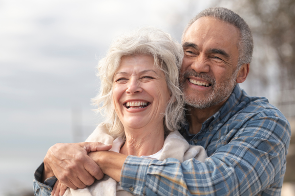 senior couple smiling showing off the improved structure in their faces after dental implant surgery