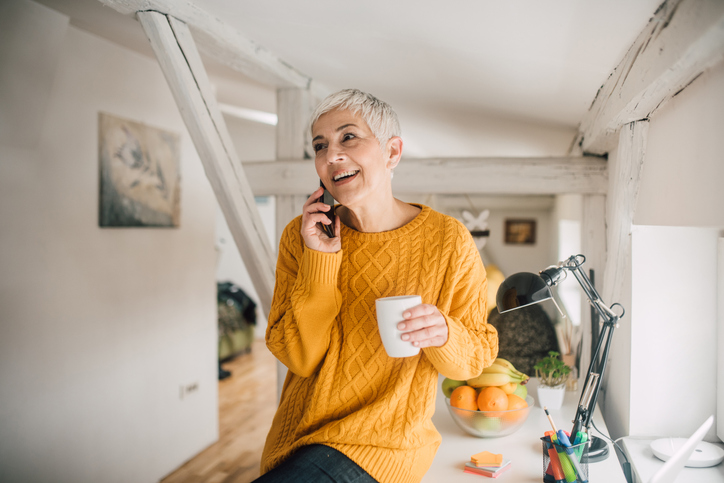 Short-haired blonde woman drinking coffee and talking on her cell. 