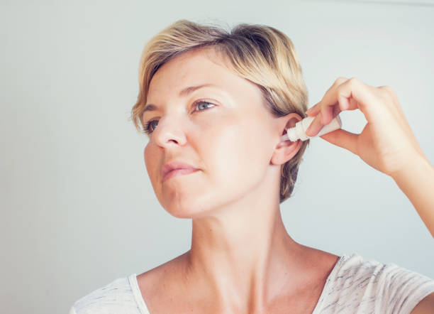 A person using over-the-counter ear drops to manage ear wax buildup
