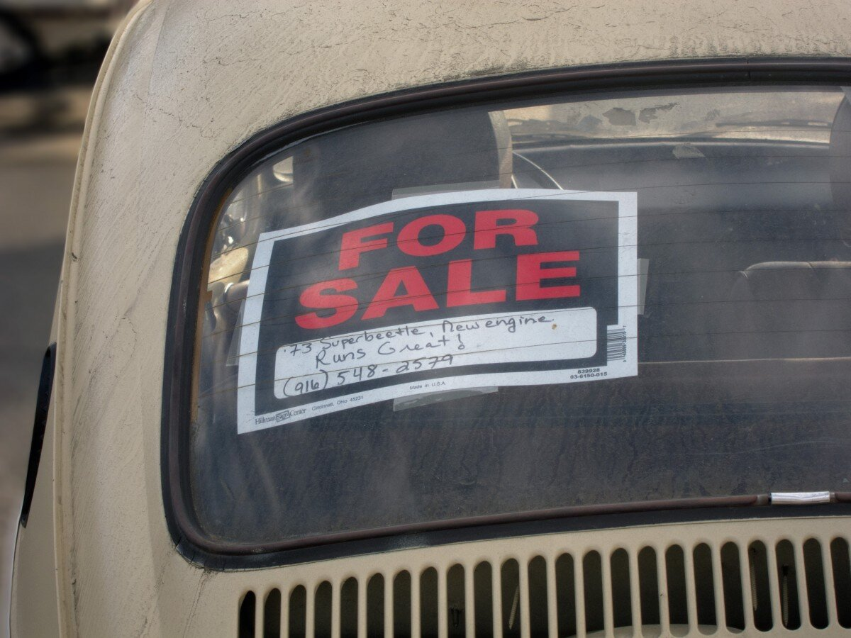 A car with a sign "Sell your junk car for cash in Springfield Gardens"