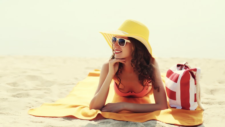 Pretty young woman in yellow hat on the beach. 