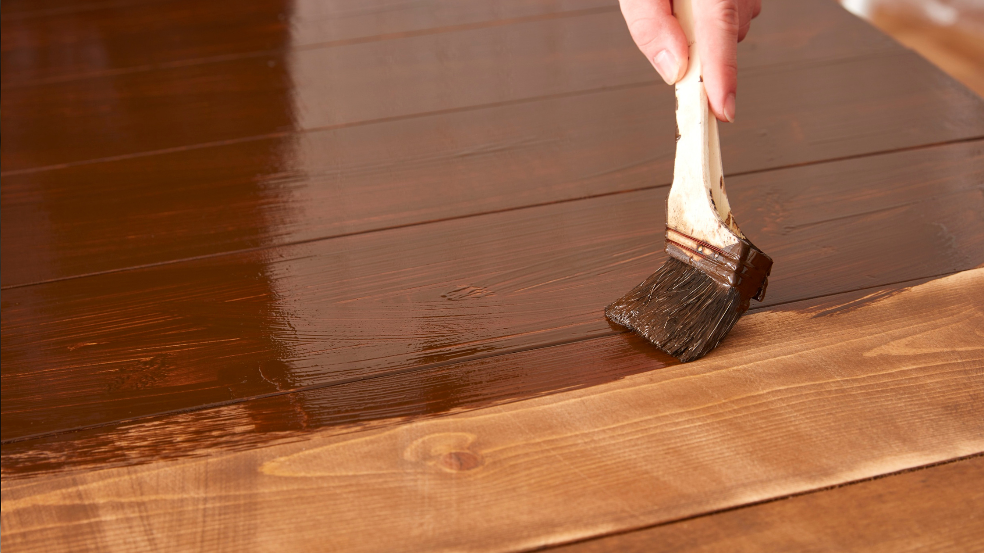 A paint brush being used to apply stain to achieve a dark look.