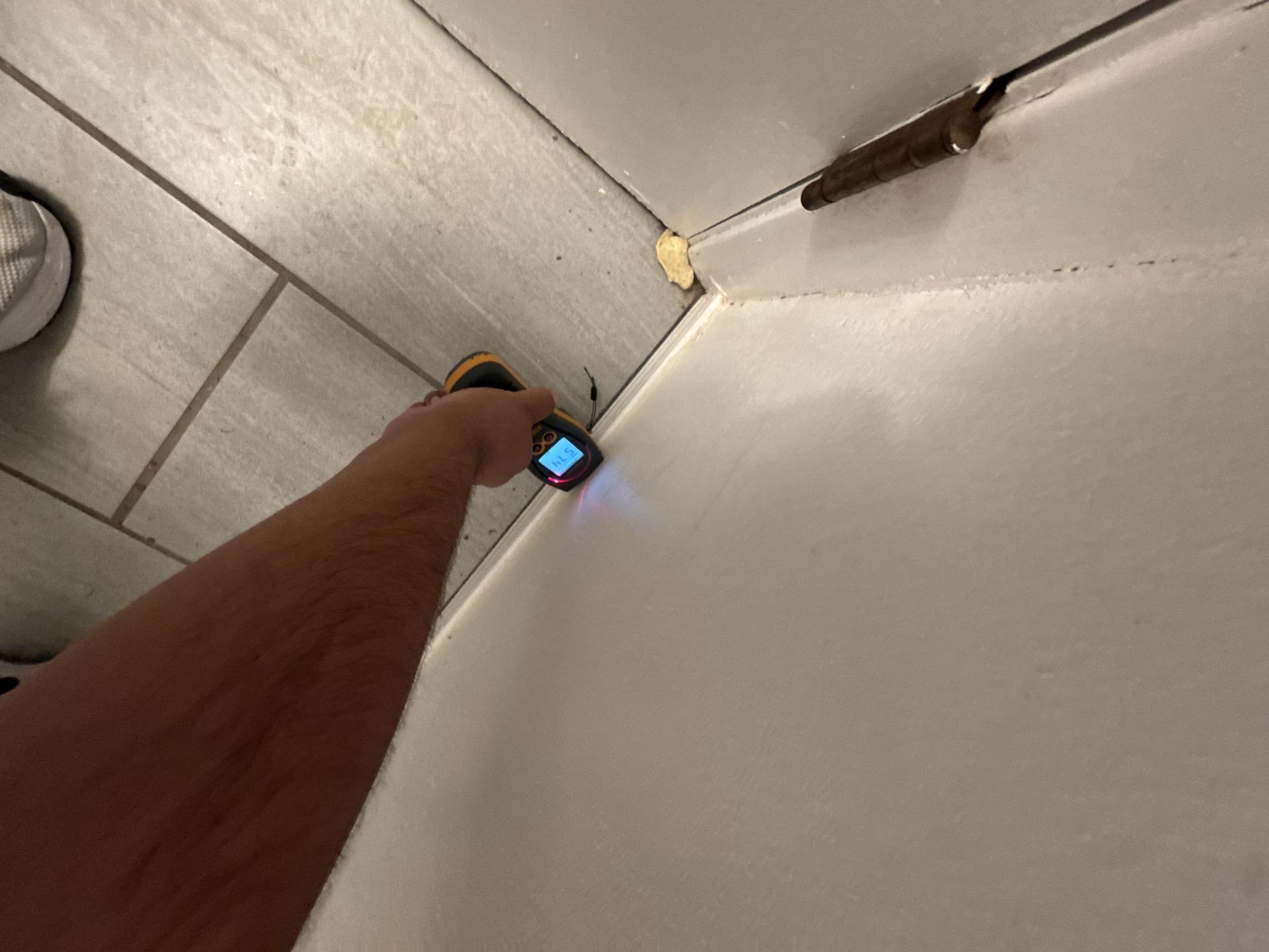 A technician in a protective suit is inspecting a wet bathroom floor, assessing the situation for potential sewage damage and health risks associated with contaminated water. The scene highlights the importance of professional sewage cleanup services to address issues like sewage backup and prevent mold growth in affected areas.