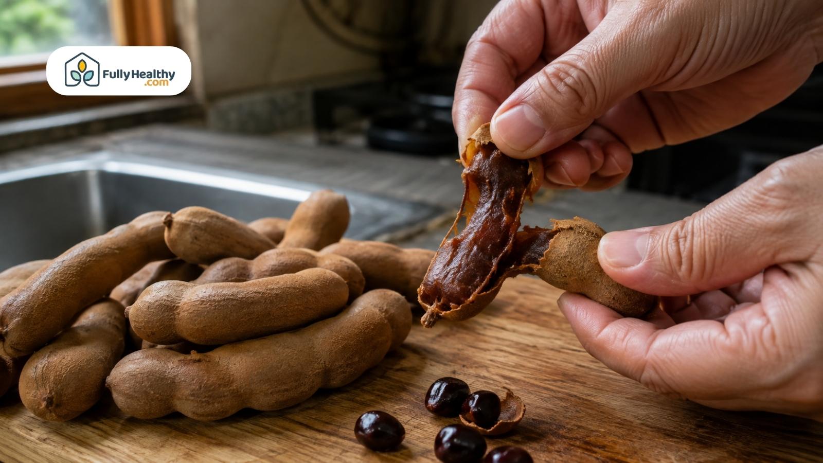 Hands opening a ripe tamarind pod revealing sticky brown pulp and seeds