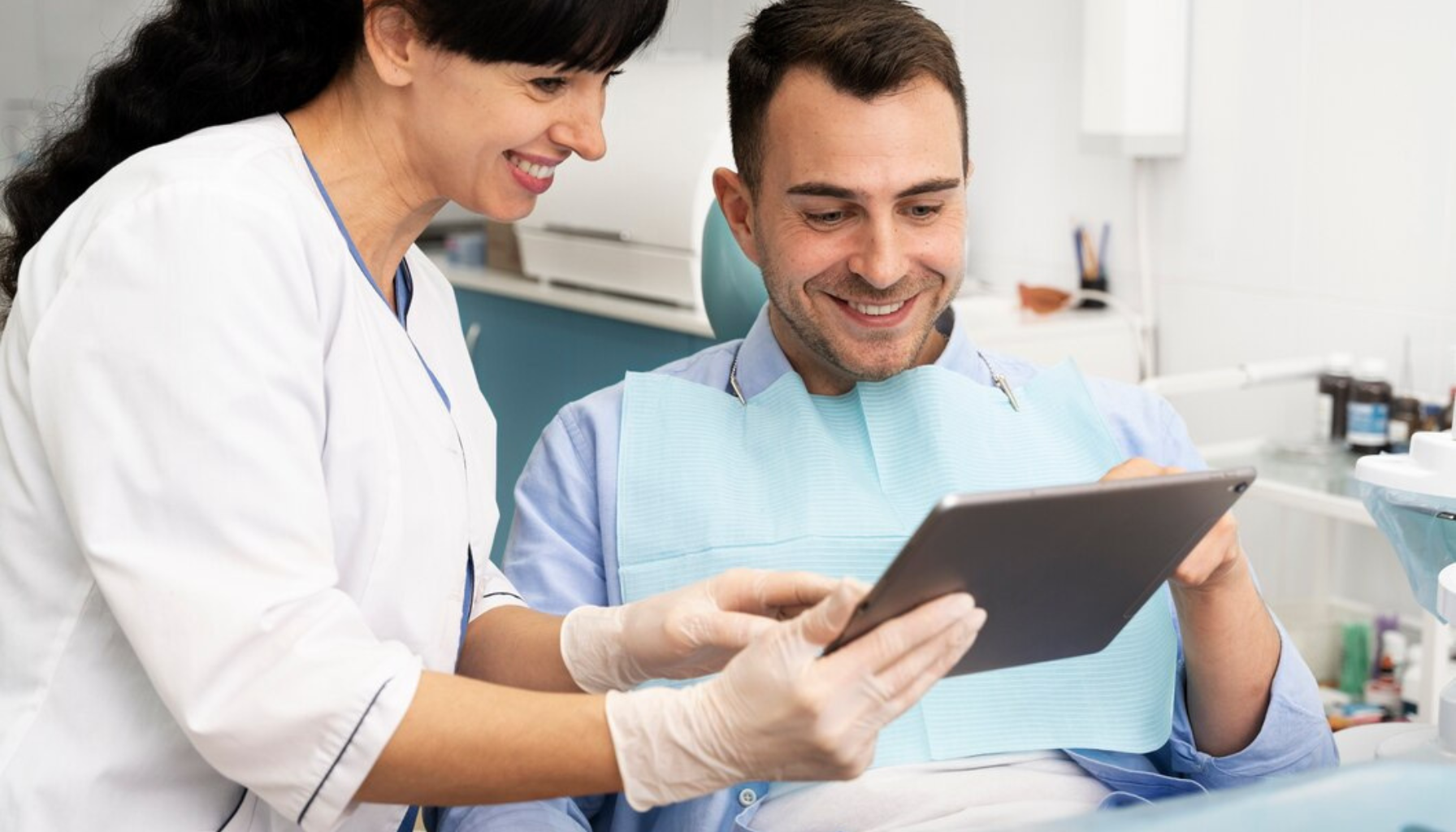 Pasient ser informasjon på nettbrett sammen med tannlege.