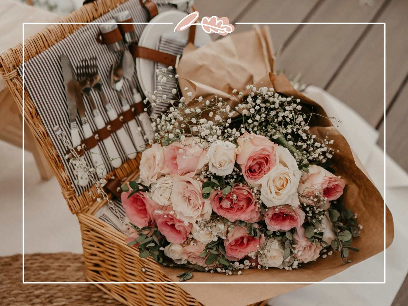 Picnic basket with cutlery and a bouquet of pink and white roses.