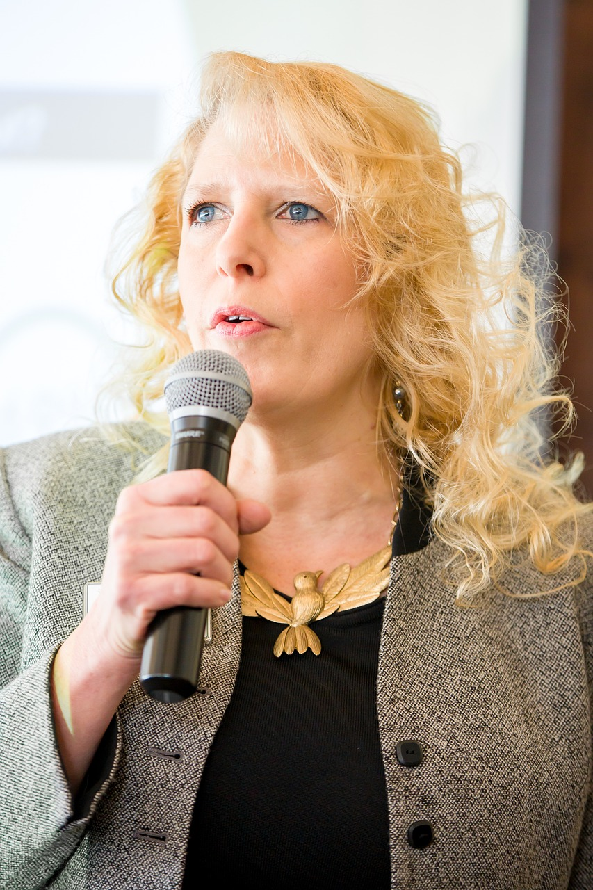 An image of a mature woman speaking into a microphone.