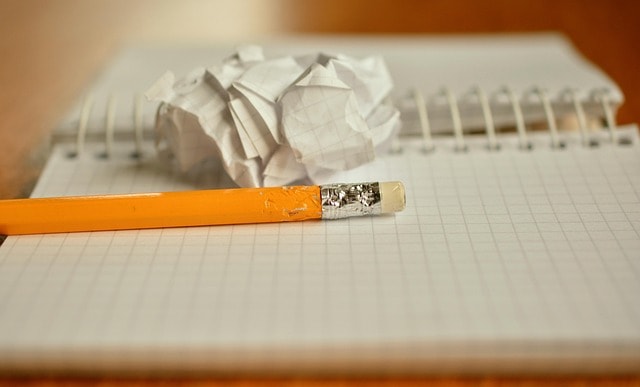 A pencil, notebook, and screwed up piece of paper representing the life of a writer.
