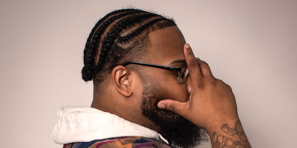 Image of a man with cornrows. Side angle shot