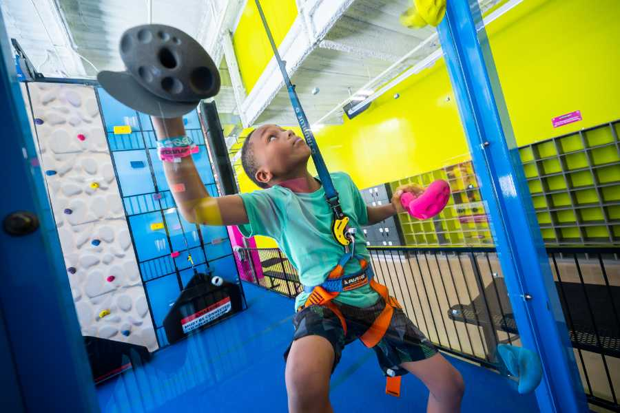 A boy climbs the Urban Air climbing wall - a fun activity for a 6-year-old birthday party. 