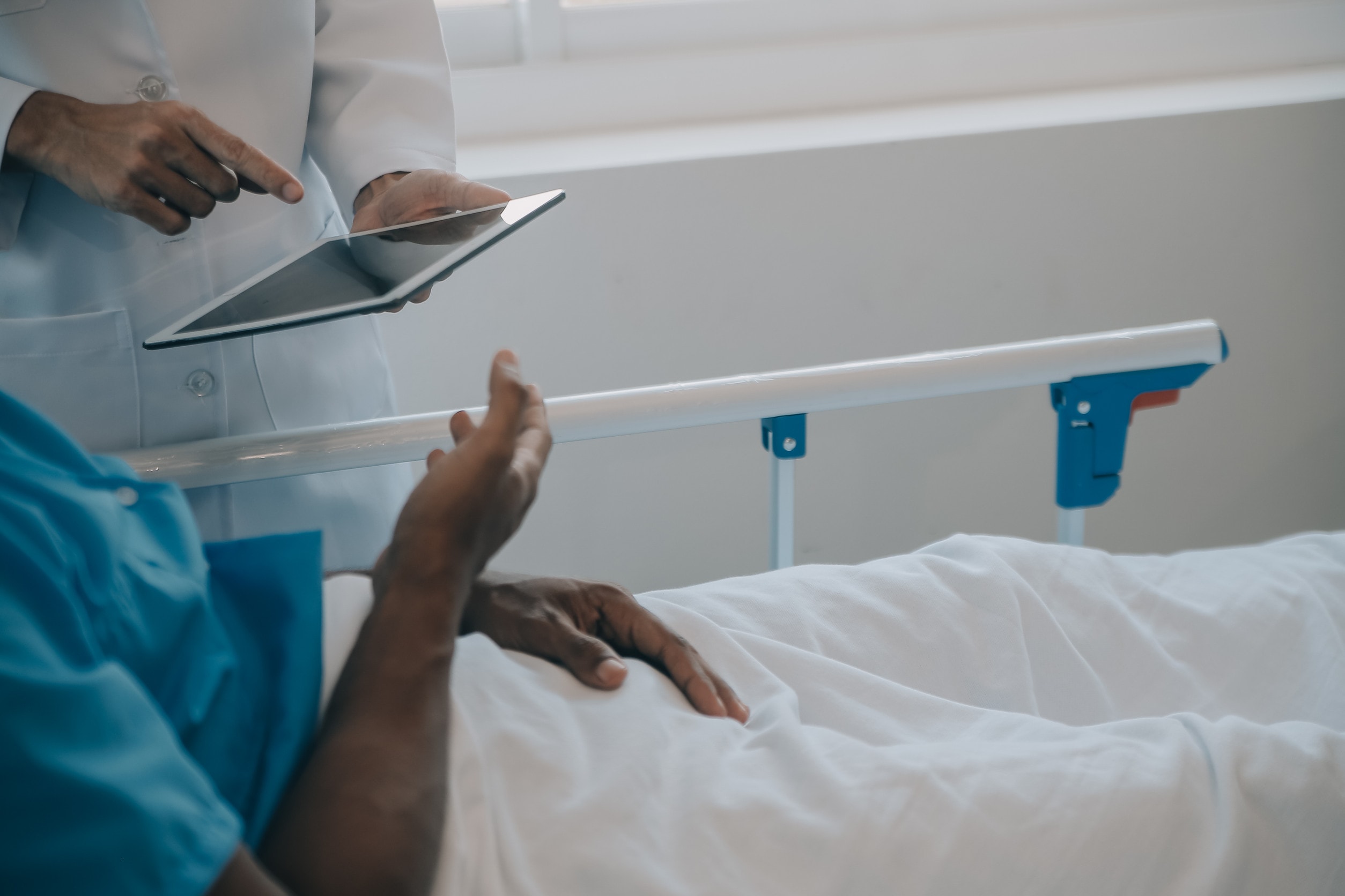 A patient with symptoms of pancreatic cancer talks to a doctor while laying in a hospital bed.