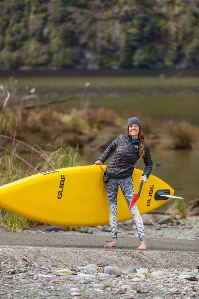 woman carrying an inflatable stand up paddle board