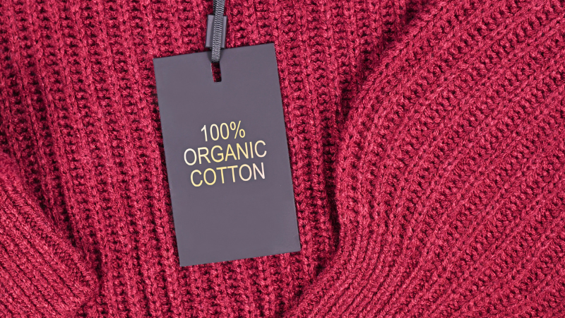 A red sweater with a label of 100% organic cotton.