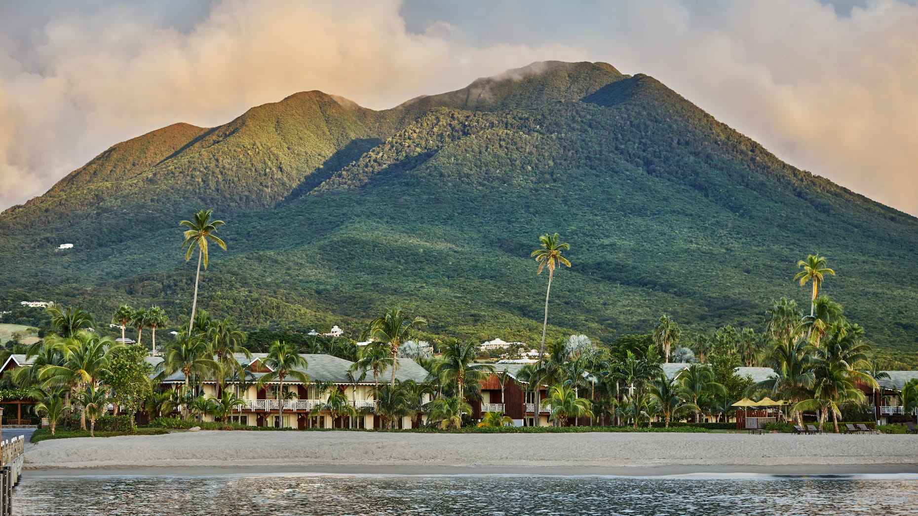 view of four seasons nevis from the water with the mountain behind the resort