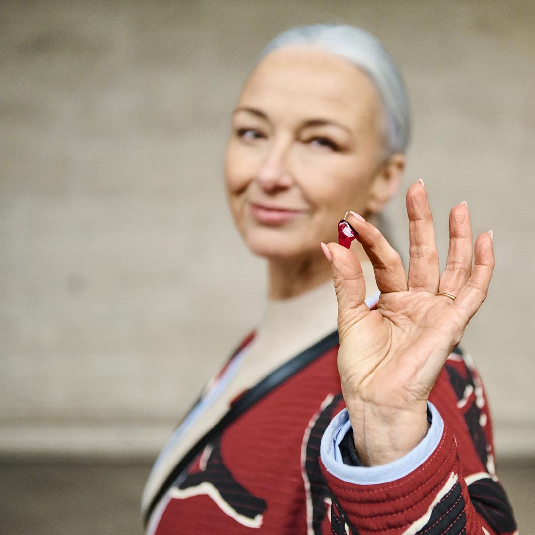 Tiny custom hearing aid held between fingertips, showcasing the discreet appearance of nearly invisible hearing aid technology