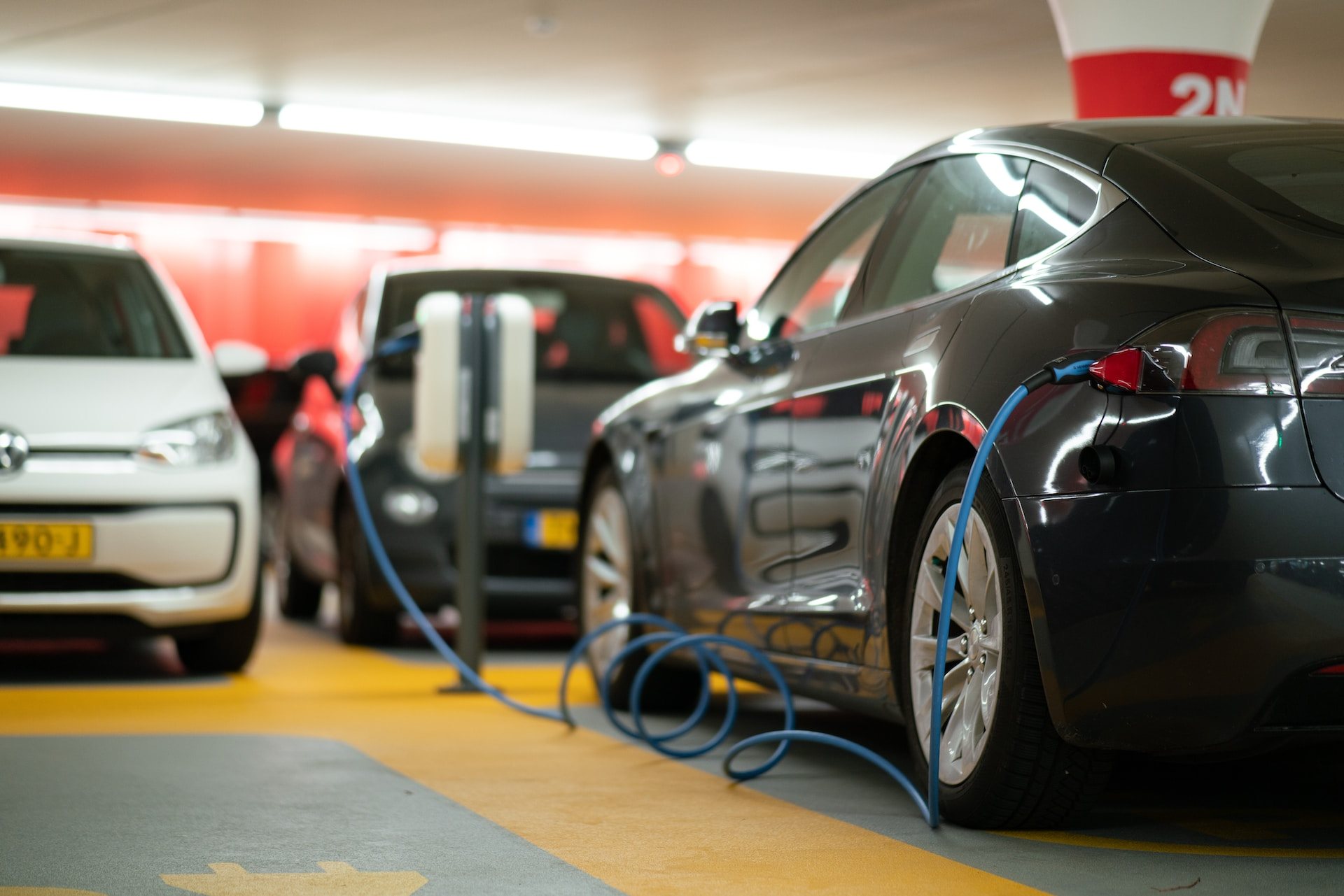 Multiple electric cars charging in a parking garage with multiple EV charging cables. 