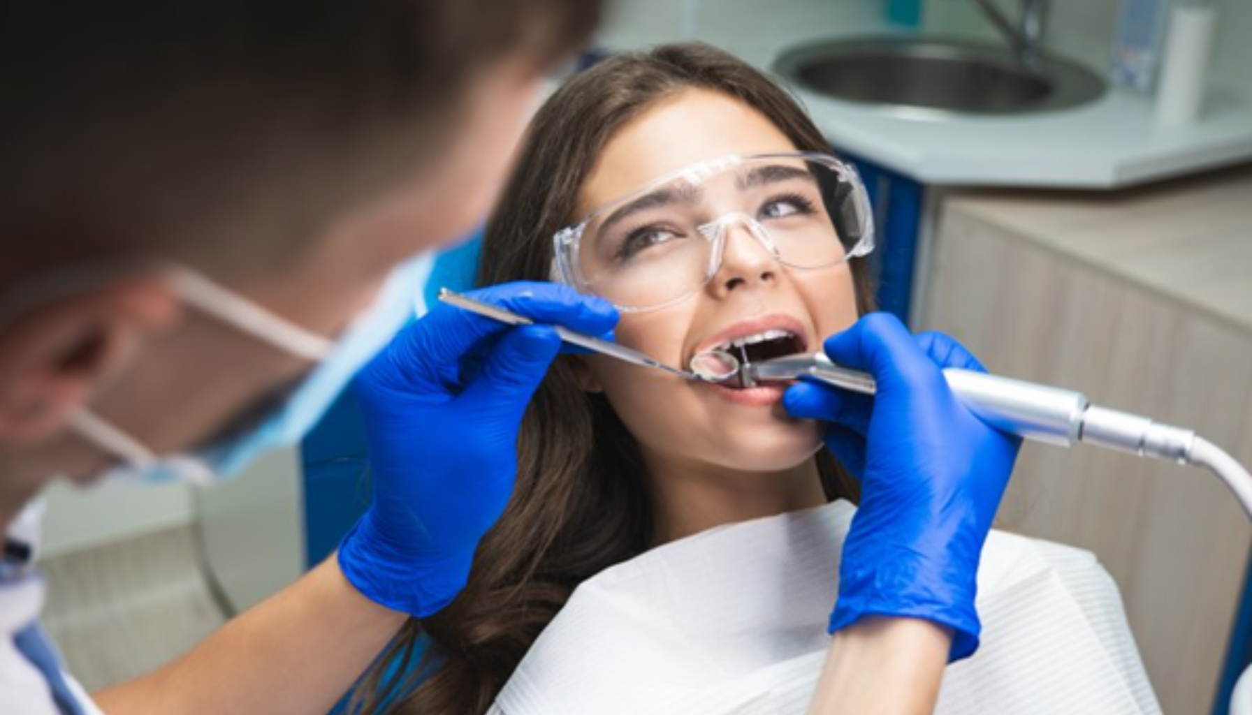 Kvinne hos tannlegen får utført tannbehandling med boremaskin.