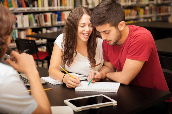 A girl sitting close to her crush in a library https://lovedevani.com/signs-a-girl-likes-you-but-is-trying-not-to-show-it