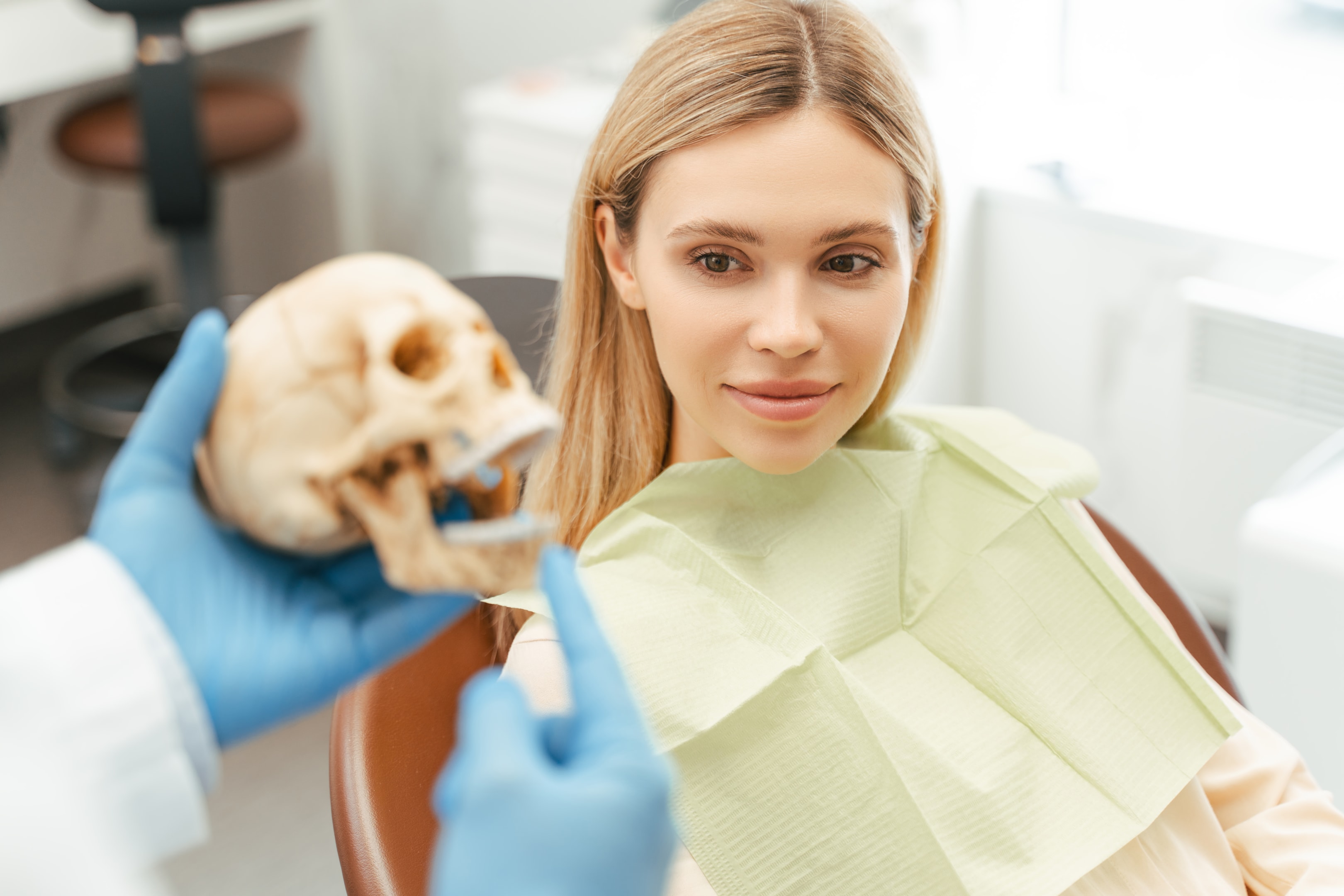 woman in dental chair being shown a skeletal modal of the correct jaw alignment 