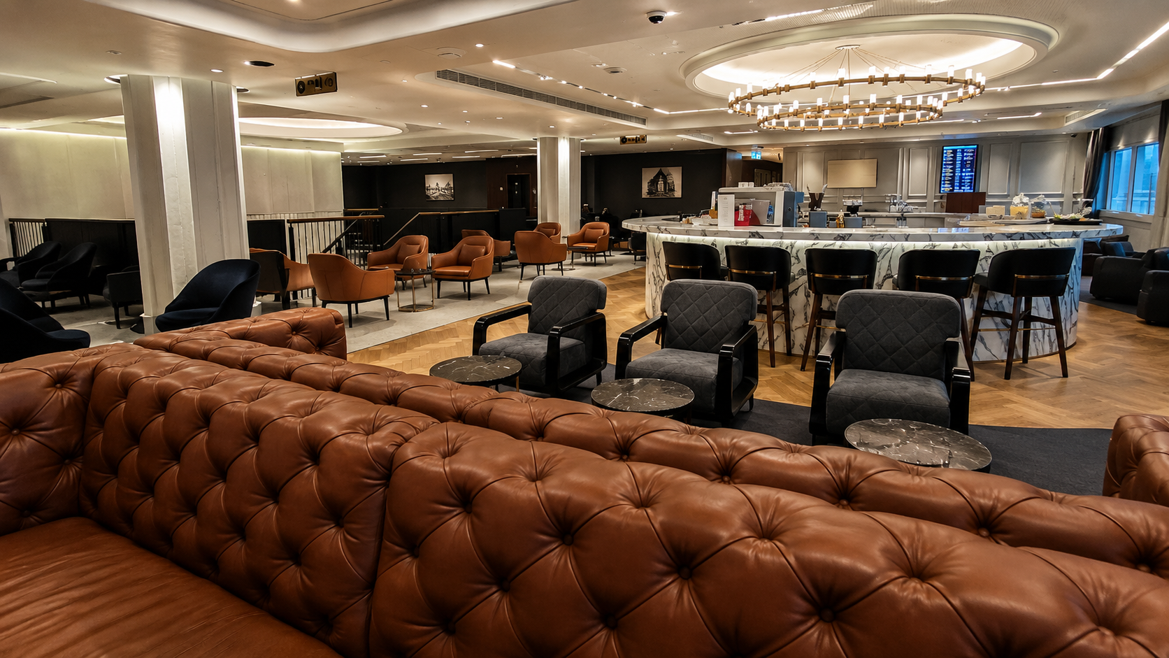 Luxury airport lounge with leather sofas, marble bar seating, armchairs, and warm modern lighting.