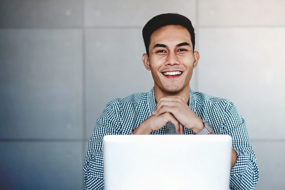 Smiling Filipino professional using a laptop, showing strong connection and confidence in a remote work environment
