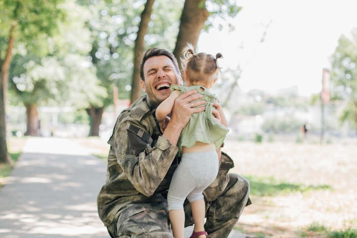 Soldier holding his little girl and smiling. 