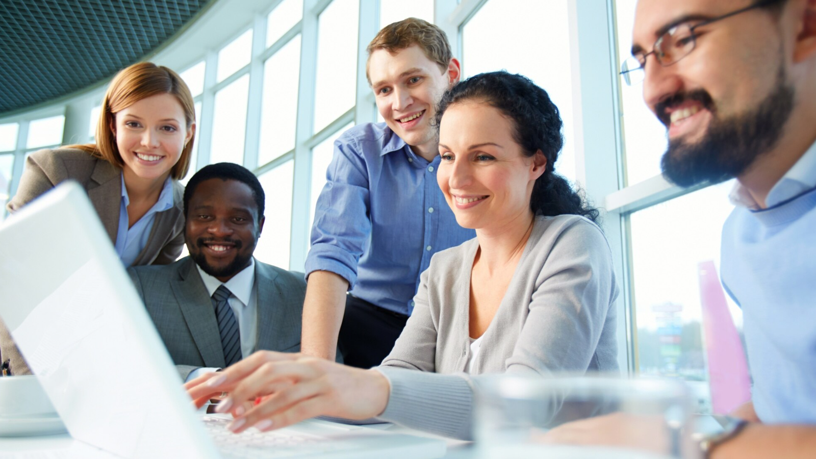Team gathered at a laptop, showing how Ten4's expertise in VoIP and emerging technologies can optimize your network performance and support your business needs.