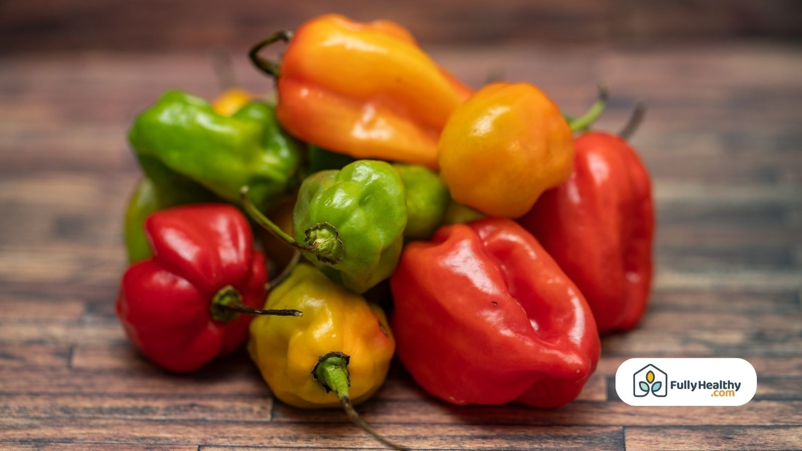 Mixed green orange and red habanero peppers on wooden surface