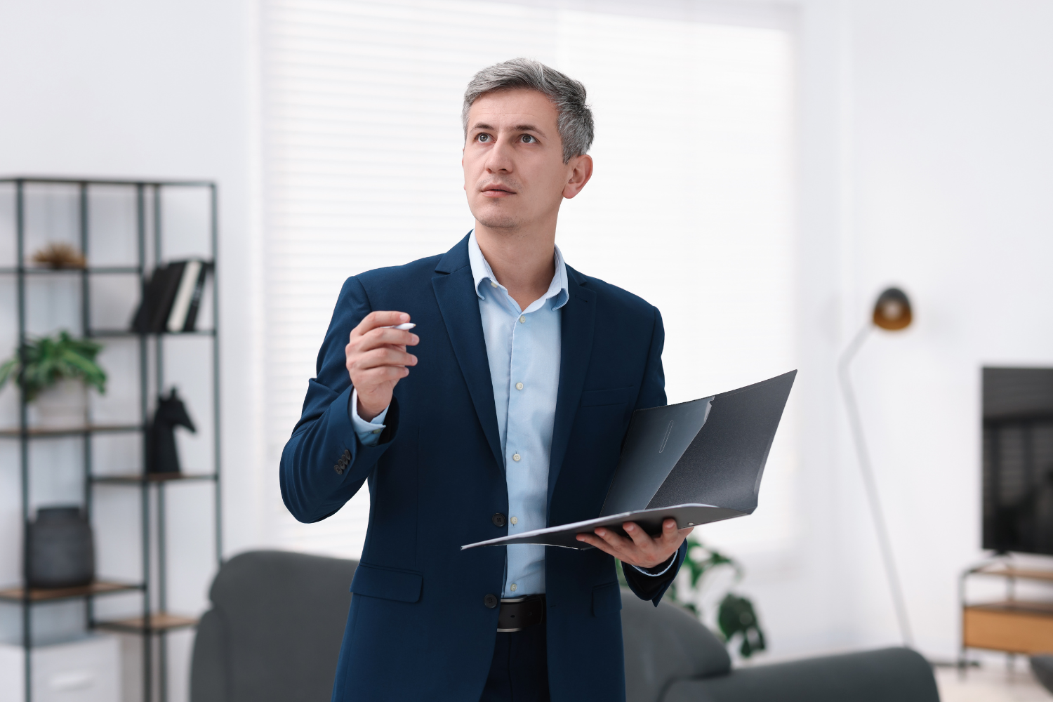 A business professional holding a folder in a living room.