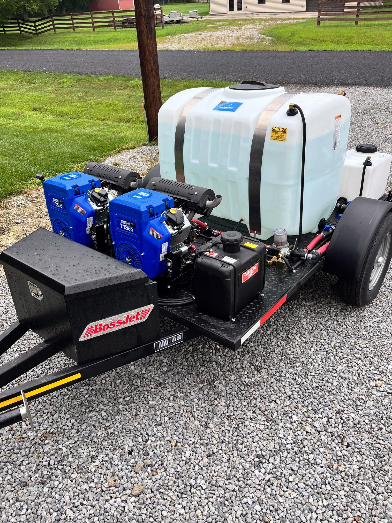 A professional trailer-mounted hydro jetting rig is parked on a residential driveway next to a home, ready to tackle clogged drains and tough clogs with high-pressure water flow. This plumbing system solution is ideal for clearing issues like grease buildup and tree root intrusion in sewer lines.