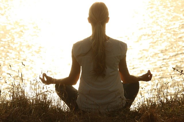 Woman meditating in front of lake