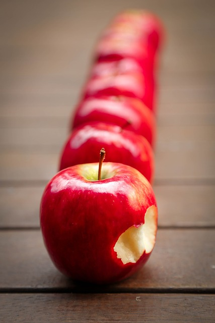 An image of a row of red apples on a wooden table.