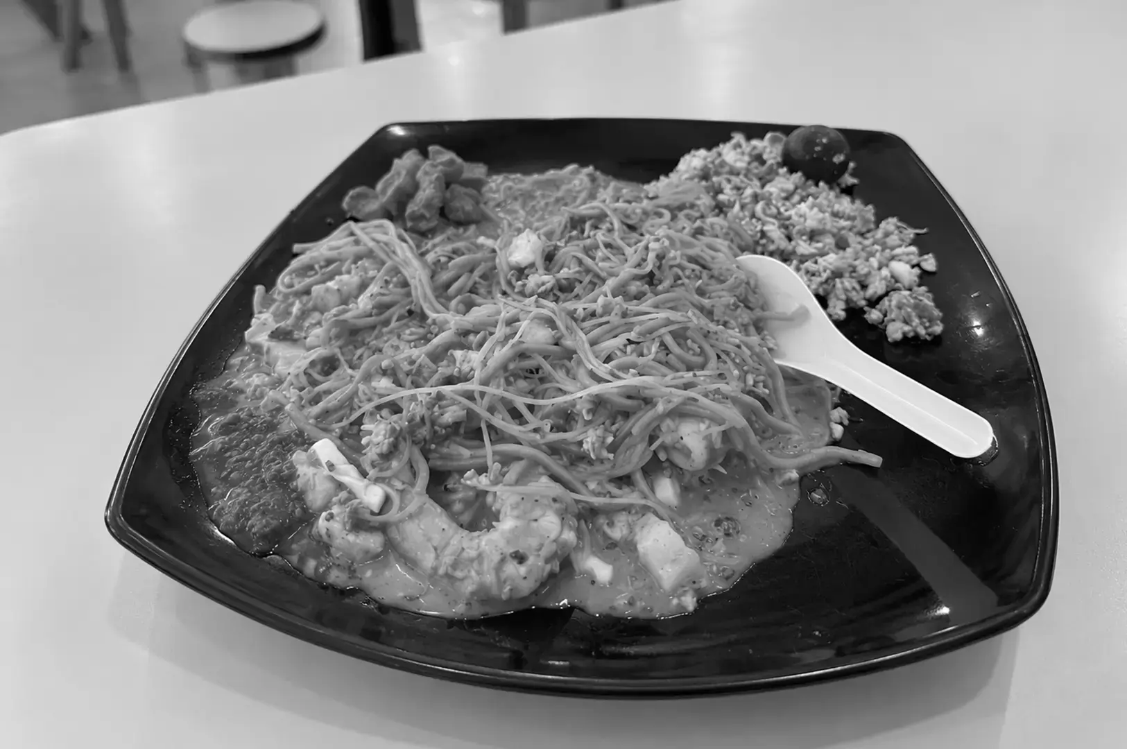 A generous plate of fried Hokkien mee tossed with noodles, seafood, and bean sprouts in a glossy sauce.