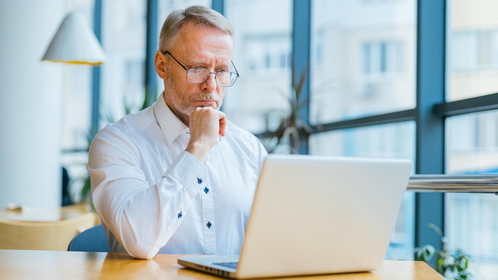 Network engineer examining laptop screen, researching how to optimize network performance for long-term business growth.