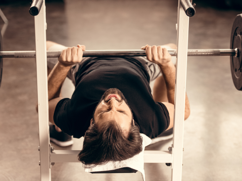 Image of an individual performing a close grip bench press for triceps growth.