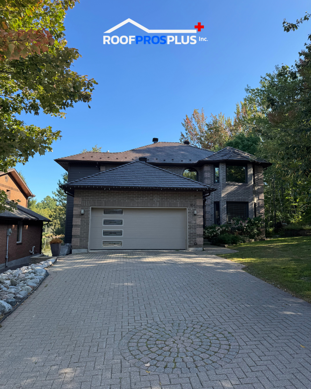 A prominent house with a metal roof, long driveway and a garage, showcasing a suburban architectural style.
