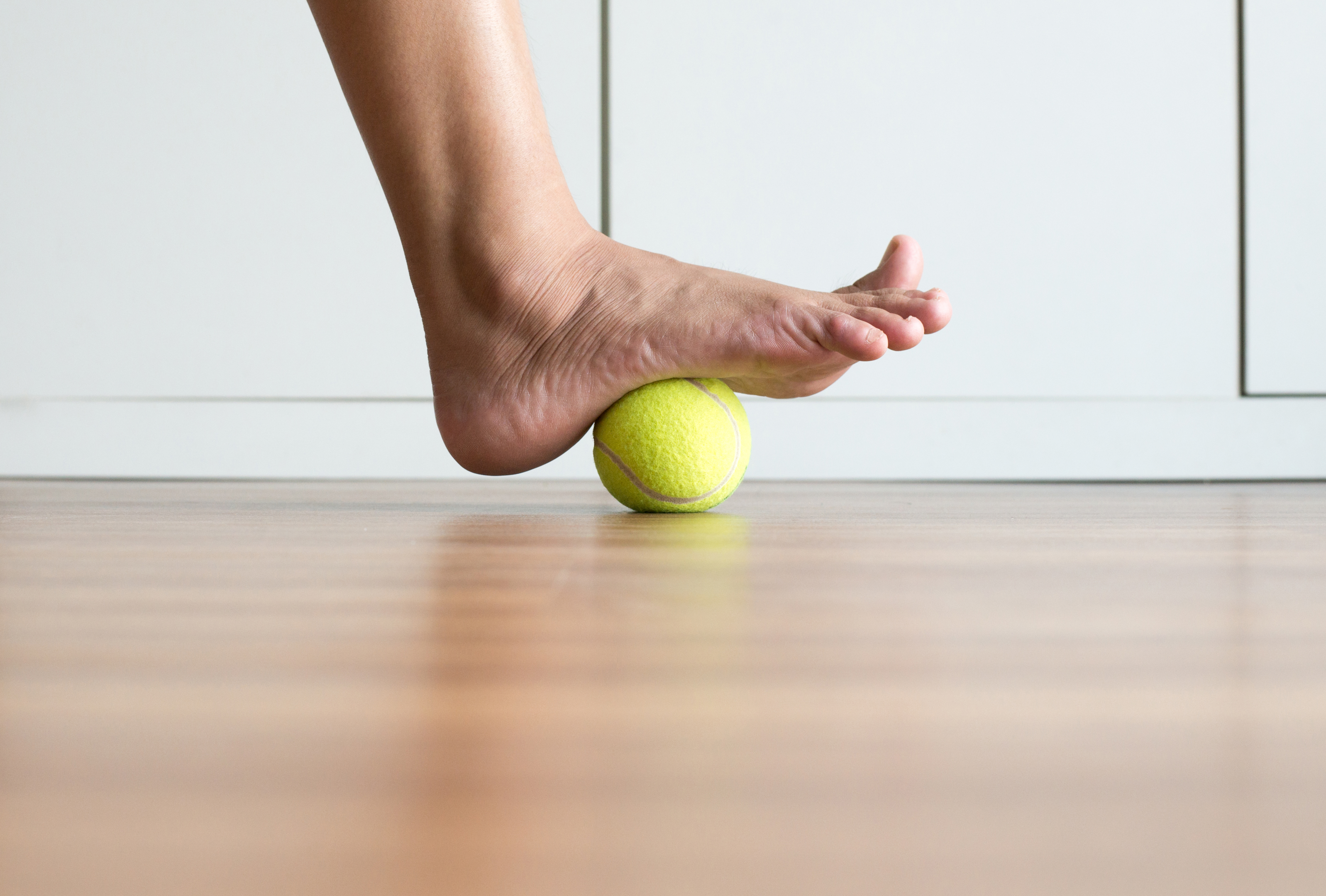 Massage av hälsporre med hjälp av en tennisboll under foten