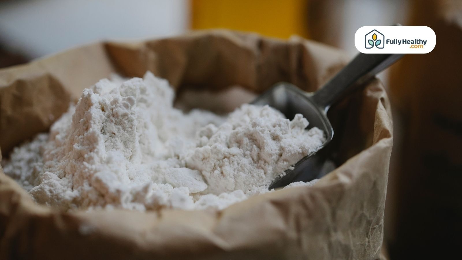 All-purpose white flour in paper bag with metal scoop on top