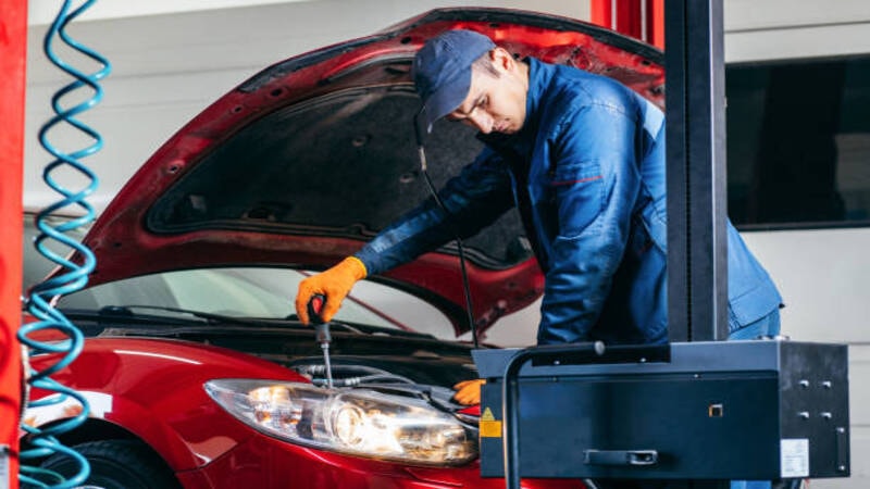 A mechanic checking the headlight of a car.