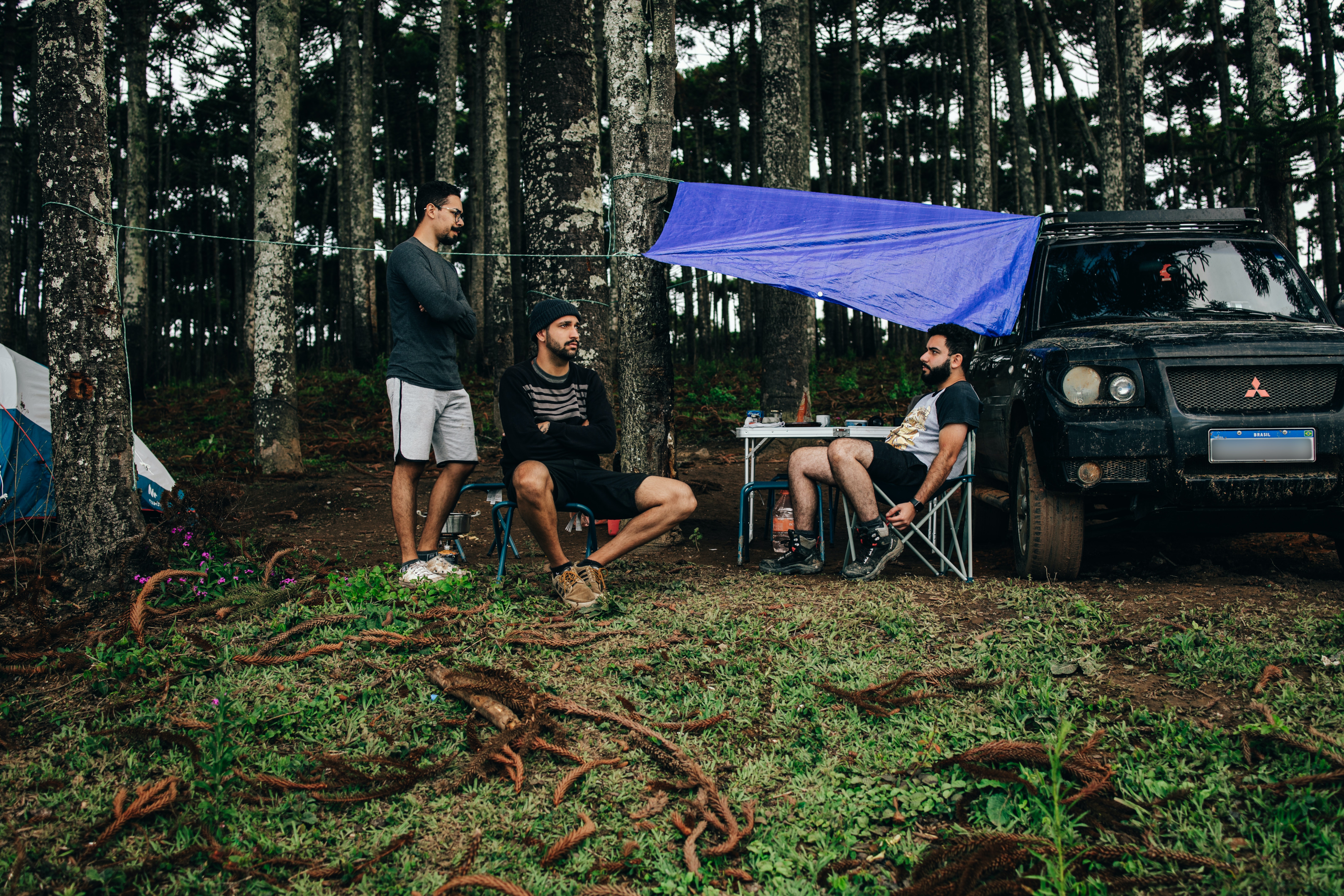 3 guys sitting under tree camping