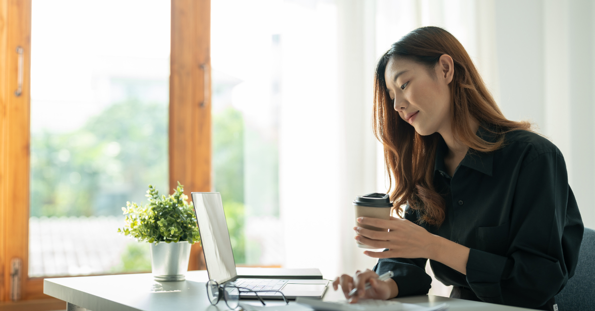 A woman working on her laptop, reviewing the income threshold for filing taxes 