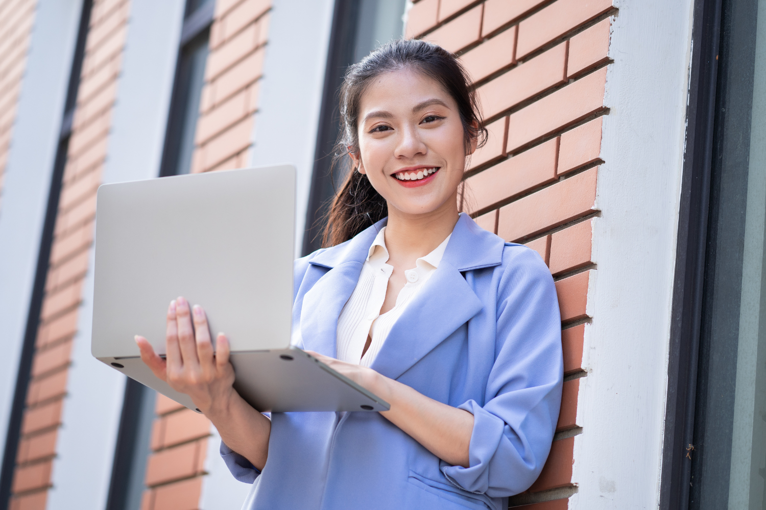 Woman smiling while holding a laptop.