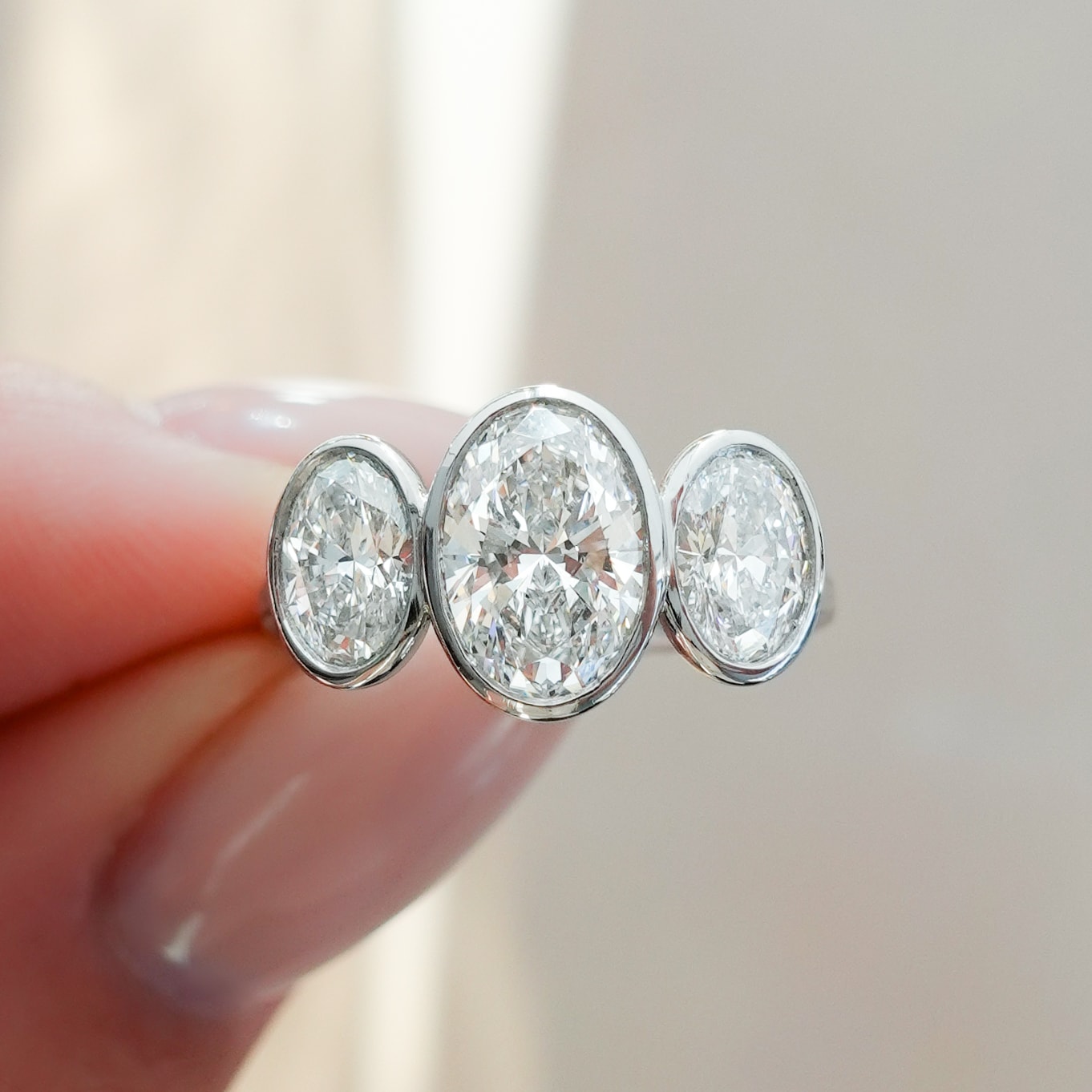Penumbra Bezel Triad Engagement Ring With Oval Cut Diamonds
