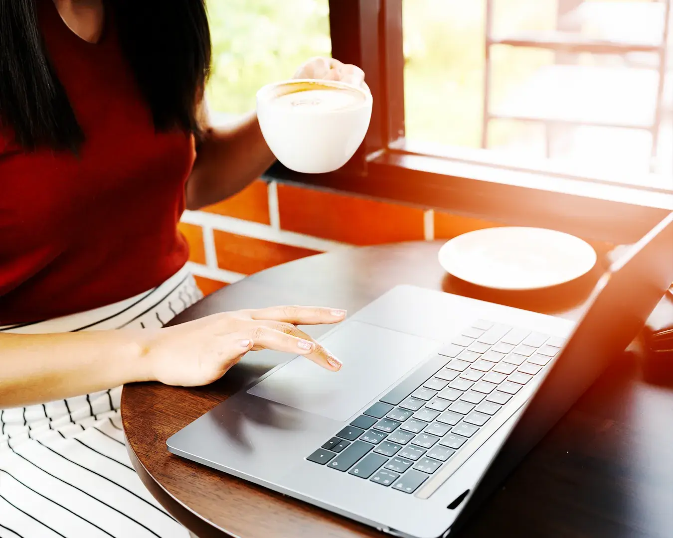 Cafe customer browsing a restaurant website on a laptop while enjoying coffee, representing online food ordering, customer experience optimization, and direct restaurant sales channels.