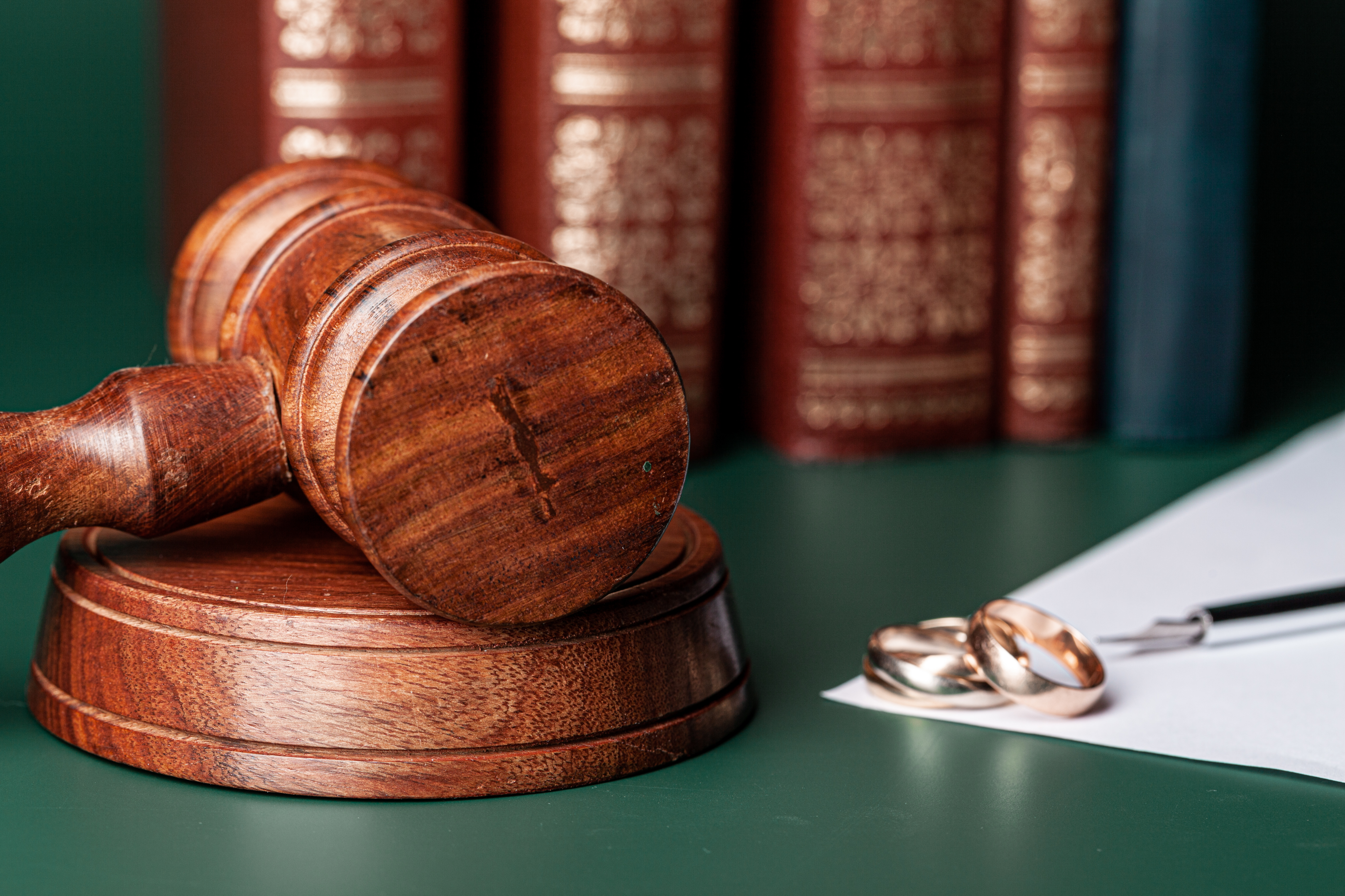 A law gavel and wedding rings on a table depict the intertwining of love and law, underscoring the legal considerations awaiting unmarried couples in California, a state where legal provisions can sometimes offer protections akin to those in marriage. It's a subtle reminder to understand your rights and safeguard your partnership.