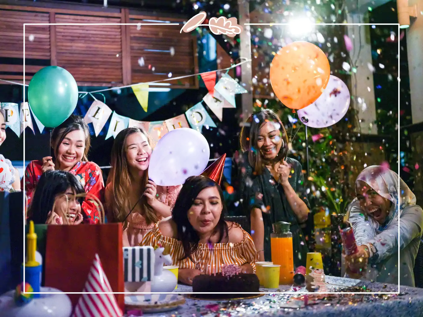 Friends celebrating a birthday with balloons, confetti, and birthday cake at a lively birthday party for a great friend. Fabulous Flowers and Gifts.